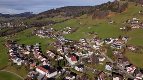 Luftaufnahme-Eines-Malerischen-Ländlichen-Dorfes-In-Bergiger-Schweizer-Landschaft