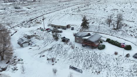 Drohnenaufnahme-Eines-Ländlichen-Hauses,-Das-Mit-Einer-Frischen-Schneeschicht-Bedeckt-Ist