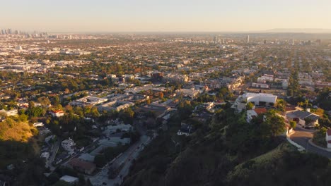 Flying-Over-Hollywood,-Pulling-Back-To-Reveal-Sunlit-City-Condos-and-Luxury-Homes-in-the-Hills