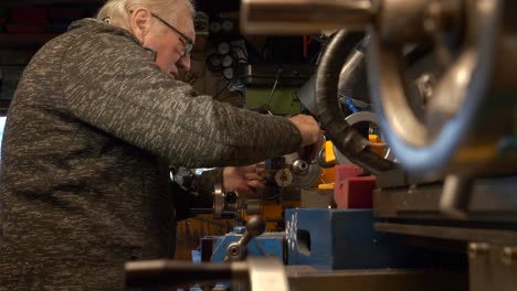 Mature-man-mechanical-engineer-working-on-lathe-machine-in-workshop