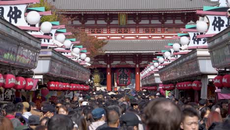 Sensō-ji-Crowded-entrance-of-Red-Temple-in-Tokyo-with-numerous-visitors-under-hanging-lanterns,-daylight