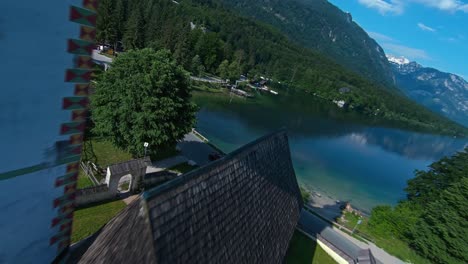 Drone-Flyover-Church-Tower-And-Stone-Bridge-By-The-Lake-Bohinj-In-Alpine-Village-Ribicev-Laz,-Slovenia