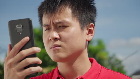 Hombre-Asiático-Perdido-Y-Confundido-Usando-El-Teléfono-Para-Navegar-En-La-Era-Digital,-Enfoque-En-Rack