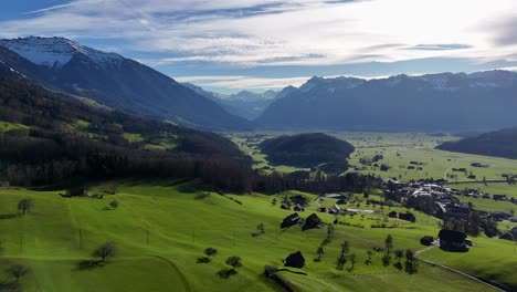 Aerial-view-over-Glarnerland-with-snowcapped-mountains-and-village-of-Rieden---Switzerland
