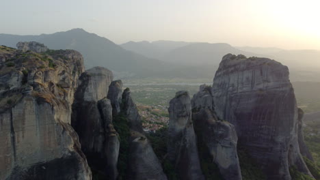 Drone-shot-of-landscape-amidst-Meteora-against-mountains-and-evening-sky