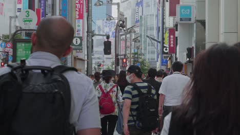 Many-pedestrians-walking-in-the-Streets-of-Shinjuku,-Tokyo,-Japan-on-an-overcast-day