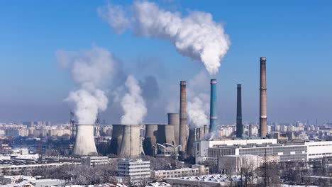 Aerial-Sweep-of-a-Coal-Power-Plant-Belching-Smoke-into-the-Upper-Atmosphere-With-a-Sprawling-Urban-Landscape-in-the-Distance,-Romania