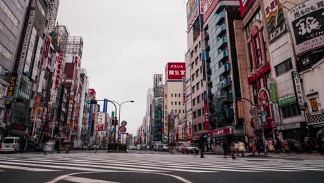 Time-Lapse-of-a-huge-crossing-in-Shinjuku,-Tokyo,-Japan-on-a-cloudy-day-with-a-lot-of-traffic-and-many-people-walking-by