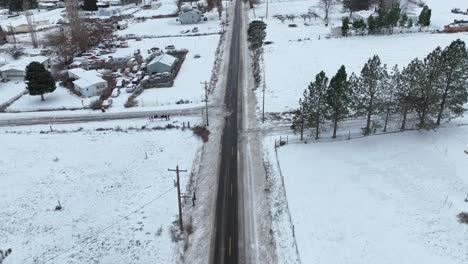 Drone-shot-tilting-up-from-the-cleared-road-to-reveal-snow-covered-land-on-the-horizon