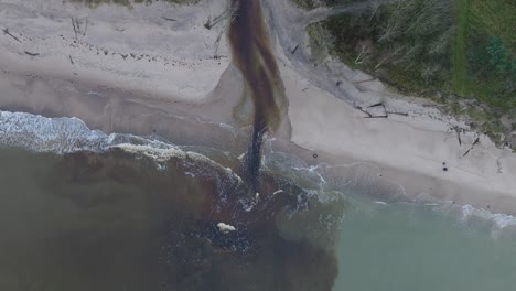 Aerial-establishing-view-of-a-small-dark-river-flowing-into-the-Baltic-sea-near-Liepaja-,-white-sand-beach,-overcast-autumn-day,-wide-descending-birdseye-drone-shot