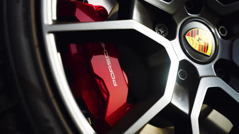 Eine-Schöne-Nahaufnahme-Eines-Porsche-Reifens-Mit-Schwarzen-Felgen,-Die-Einen-Leuchtend-Roten-Hochleistungsbremskanal-Und-Das-Schöne-Porsche-Logo-Zeigt