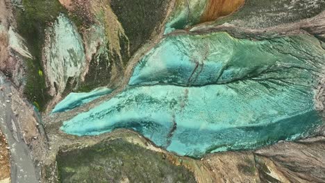 Aerial-drone-azimuthal-movement-to-the-right-at-medium-altitude,-revealing-the-entirety-of-Grænihryggur,-the-green-rock,-in-Landmannalaugar,-Iceland,-emphasizing-the-medium-tones-of-orange-and-green