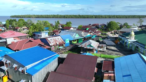 Resident's-houses-and-mosques-facing-a-wide-river,-dense-forest-and-beautiful-blue-sky-in-Asmat,-Papua,-Indonesia