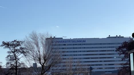 Airplane-at-blue-sky-flying-behind-university-hospital-in-Frankfurt