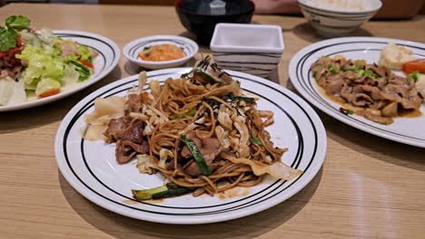 Twisting-a-few-strands-of-stir-fried-noodles-with-a-pair-of-chopsticks-while-having-dinner-in-a-restaurant-in-Bangkok,-Thailand