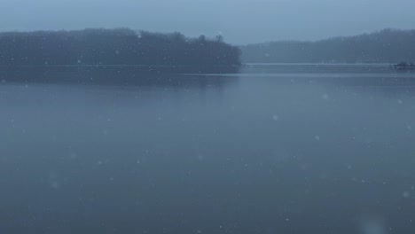 Beautiful-and-calm-gentle-slow-motion-snowfall-over-a-calm,-quiet-mountain-lake