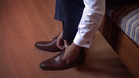 Un-Hombre-Terminando-De-Vestirse-Con-Un-Traje-Formal,-Abrochándose-Los-Zapatos