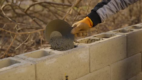 Worker-Pouring-Wet-Concrete-Or-Cement-From-Wheelbarrow-On-Wall-In-Construction