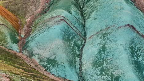 Aerial-drone-frontal,-very-close-shot-sliding-down-the-face-of-Grænihryggur,-the-green-rock,-in-Landmannalaugar,-Iceland,-emphasizing-the-medium-tones-of-orange-and-green