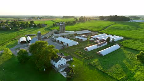 High-aerial-orbit-of-farm-buildings-and-greenhouse-barns,-silos