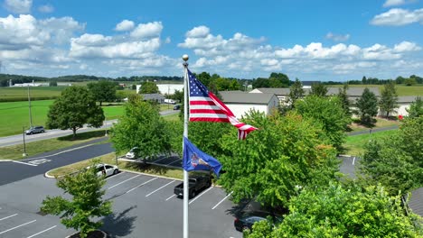 American-flag-waving-against-bright-blue-sky-and-green-farmland-in-rural-USA