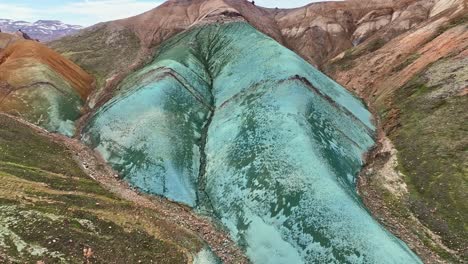 Aerial-drone-low-altitude,-fixed-top-down-view-with-a-very-slow-movement,-capturing-Grænihryggur,-the-green-rock-in-Landmannalaugar,-Iceland,-showcasing-medium-tones-of-orange-and-green
