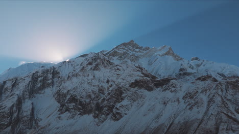 Early-sunrise-from-Annapurna-Mountain-Range,-Nepal,-Drone-reveals-peak-shining,-blue-sky,-snow,-and-amazing-time-lapse-shot,-Touristic-mountaineering-adventure-4K