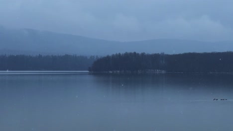 Beautiful-and-calm-gentle-snowfall-over-a-calm,-quiet-mountain-lake