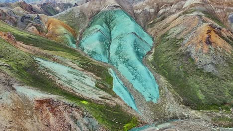 Aerial-drone-smooth-little-top-movement-on-the-face-of-Grænihryggur,-the-green-rock,-in-Landmannalaugar,-Iceland,-emphasizing-the-medium-tones-of-orange-and-green