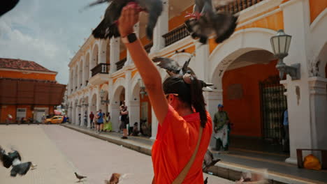 Young-female-traveler-playing-with-pigeons-on-the-streets-of-Cartagena-de-las-Indias,-Colombia,-South-America