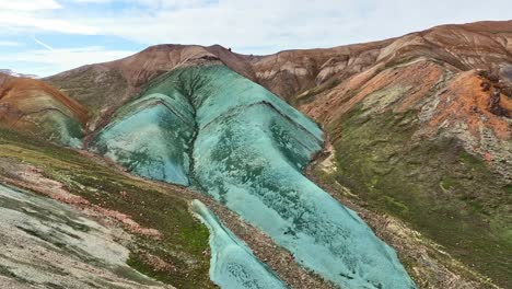 Aerial-drone-direct-forward-low-altitude-view-over-Grænihryggur,-the-green-rock,-in-Landmannalaugar,-Iceland