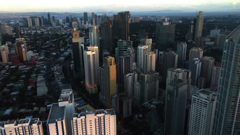 Aerial-view-tilting-toward-the-Buendia-ave,-sunset-in-Makati,-Manila,-Philippines