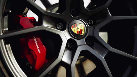 Nahaufnahme-Einer-Porsche-Felge-Mit-Leuchtend-Rotem-Performance-Bremskanal-Und-Wunderschönem-Porsche-Emblem