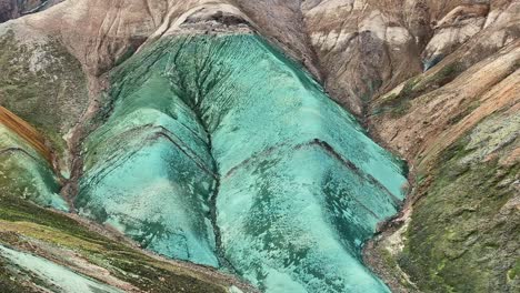 Aerial-drone-orbit-movement,-close-up-shot-of-the-middle-section-of-Grænihryggur,-the-green-rock-in-Landmannalaugar,-Iceland,-emphasizing-the-medium-tones-of-orange-and-green