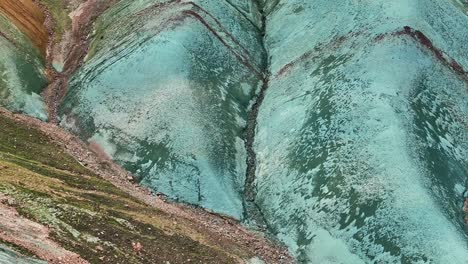 Aerial-drone-close-up,-fast-movement-from-bottom-to-top-along-the-left-side-of-Grænihryggur,-the-green-rock,-in-Landmannalaugar,-Iceland,-showcasing-medium-tones-of-orange-and-green