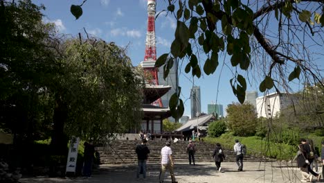 Visitors-climb-steps-to-Zojo-ji-Buddhist-temple-with-city-communication-tower-backdrop