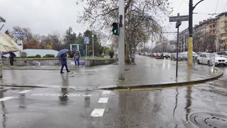 crossing-a-crosswalk-at-Evlogi-and-Hristo-Georgievi-Boulevard,-near-the-Eagles'-Bridge,-with-a-group-of-people,-in-the-rain
