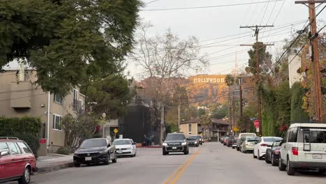 Vista-De-La-Calle-De-Los-Ángeles-Con-El-Icónico-Cartel-De-Hollywood-A-Lo-Lejos,-Automóviles-Y-Líneas-Eléctricas