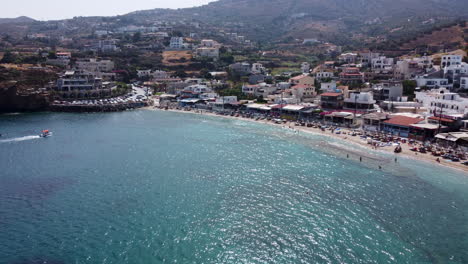 A-wide-drone-shot-of-the-boats-and-beaches-in-Agia-Pelagia,-a-resort-town-in-Crete