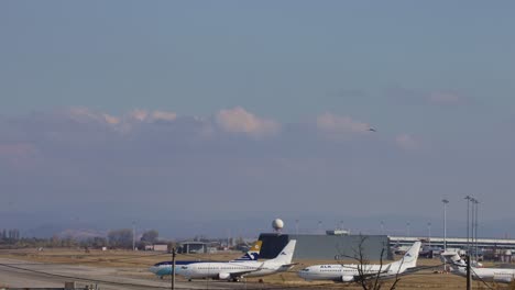 Time-lapse-of-the-airport,-some-planes-are-parked-and-getting-serviced-and-some-planes-are-moving-in-the-background