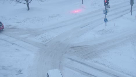Snowy-winter-city-roads,-car-traffic-drive-through-dusk-intersection