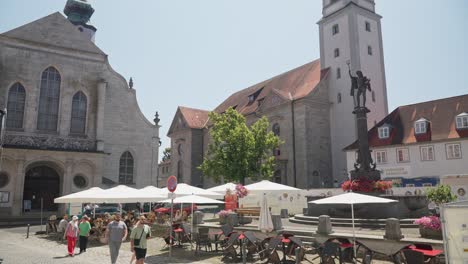 Sunny-day-at-a-Lindau-cafe-with-locals-enjoying-the-weather-near-historical-buildings-and-a-statue
