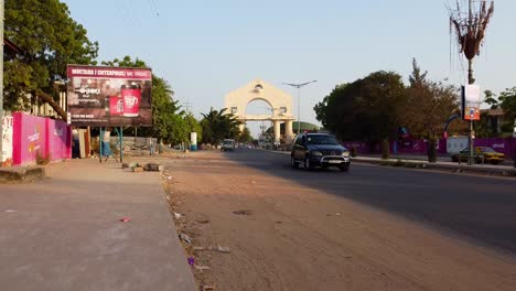 Toma-Descendente-Muy-Lenta-Del-Arco-22-En-La-Entrada-De-Banjul,-Junto-A-La-Autopista-En-La-Escuela-Secundaria-Superior-De-Gambia.