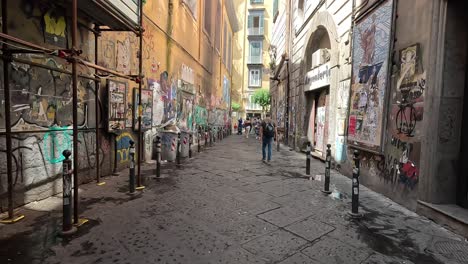 Toma-Pov-De-Caminar-Por-Una-Calle-Estrecha-Y-Sucia-Con-Grafito-En-El-Centro-De-La-Ciudad-De-Nápoles-En-Italia