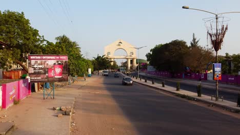 Sehr-Langsam-Absteigende-Luftaufnahme-Des-Verkehrs-Am-Arch-22-Banjul-Entrance-Highway,-Gambia-–-Westafrika