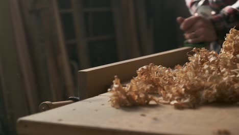 Carpenter-planing-wood-in-moody-workshop