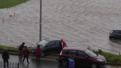 Nachbarn-Schließen-Sich-Bei-Rauem-Wetter-In-Irland-Zusammen,-Um-Autos-Vor-Überschwemmungen-Zu-Retten