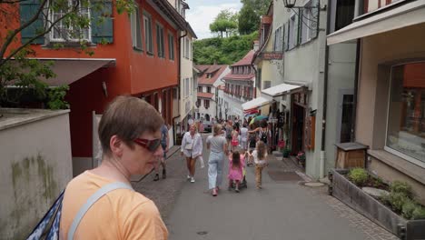 Crowded-European-street-in-Meersburg-with-tourists-walking,-old-buildings,-summer-vibe,-handheld-shot