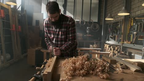 Carpenter-planing-wood-in-moody-workshop