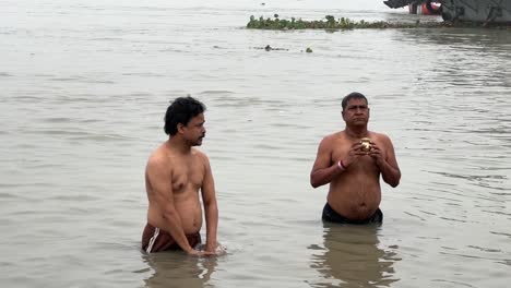Static-shot-of-men-talking-the-holy-dip-and-praying-in-foggy-winter-morning-during-Sankranti-with-seascape-in-the-background